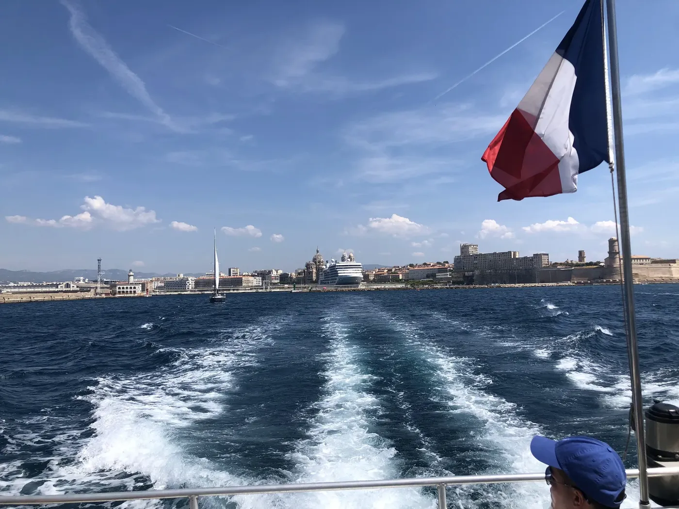 Näkymä veneen perästä Marseillen rantabulevardille, Ranskan lippu liehuu